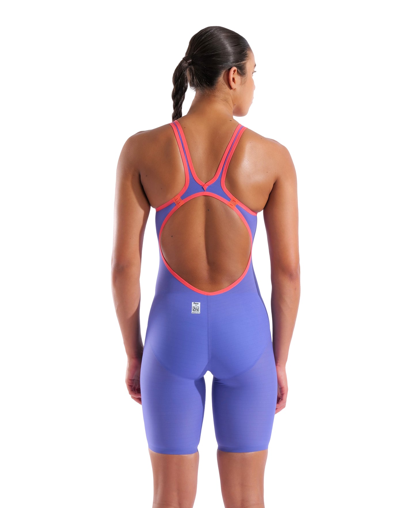 A woman with dark braided hair is shown from the back wearing the Arena Women's Open-Back Powerskin Carbon Air2 Kneeskin - Limited Edition Eclipse Glare, featuring an open-back design and knee-length cut in blue with pink trim.